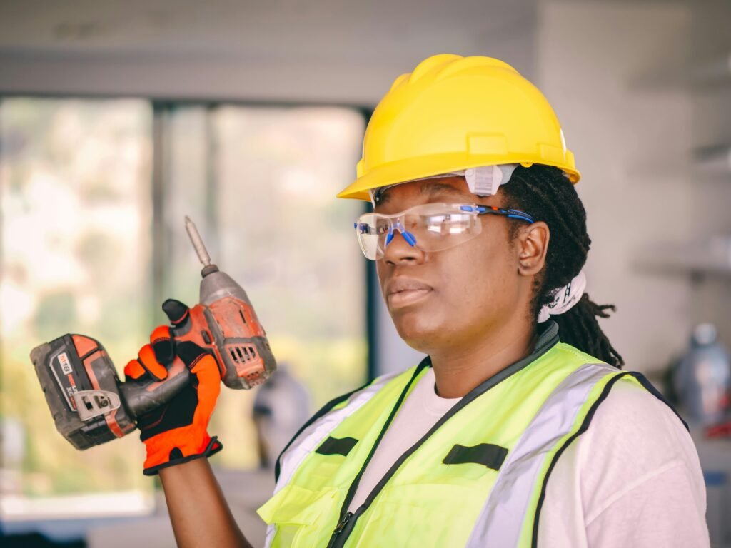 pexels-photo-8486926-8486926 Confident female construction worker wearing safety gear and holding a drill indoors.